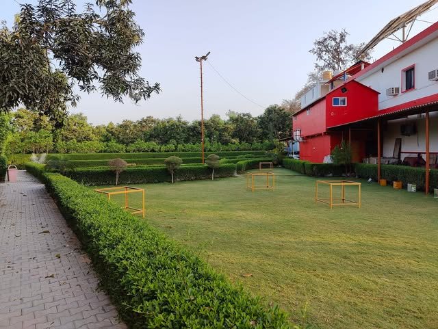 The lawn at Manu Resort, with hedges, a brick path, and the red building beside it